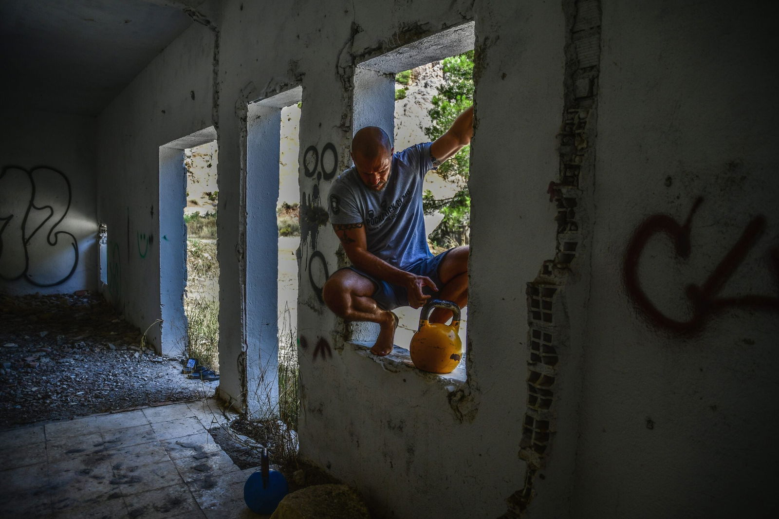 A person with a kettlebell sitting in an empty foundation