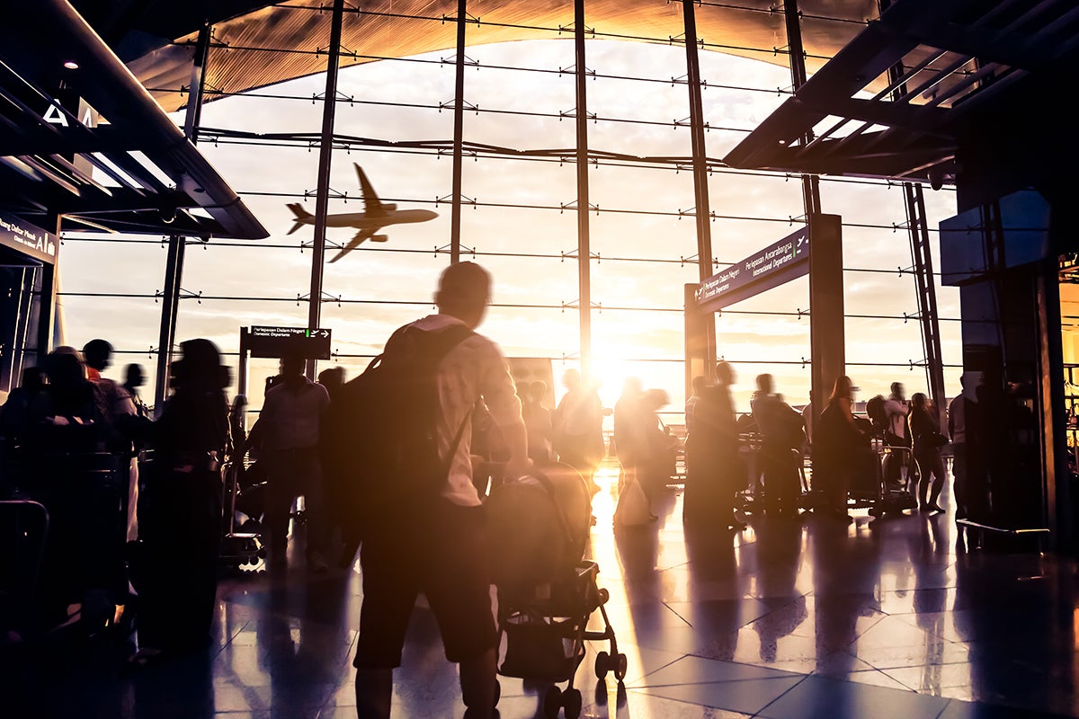 crowded airport with airliner flying overhead