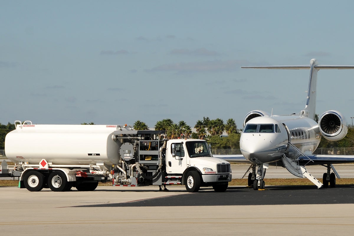 A business jet parked next to a refueling truck