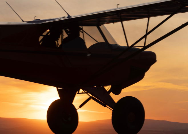 A small aircraft soars through the skies at sunset.
