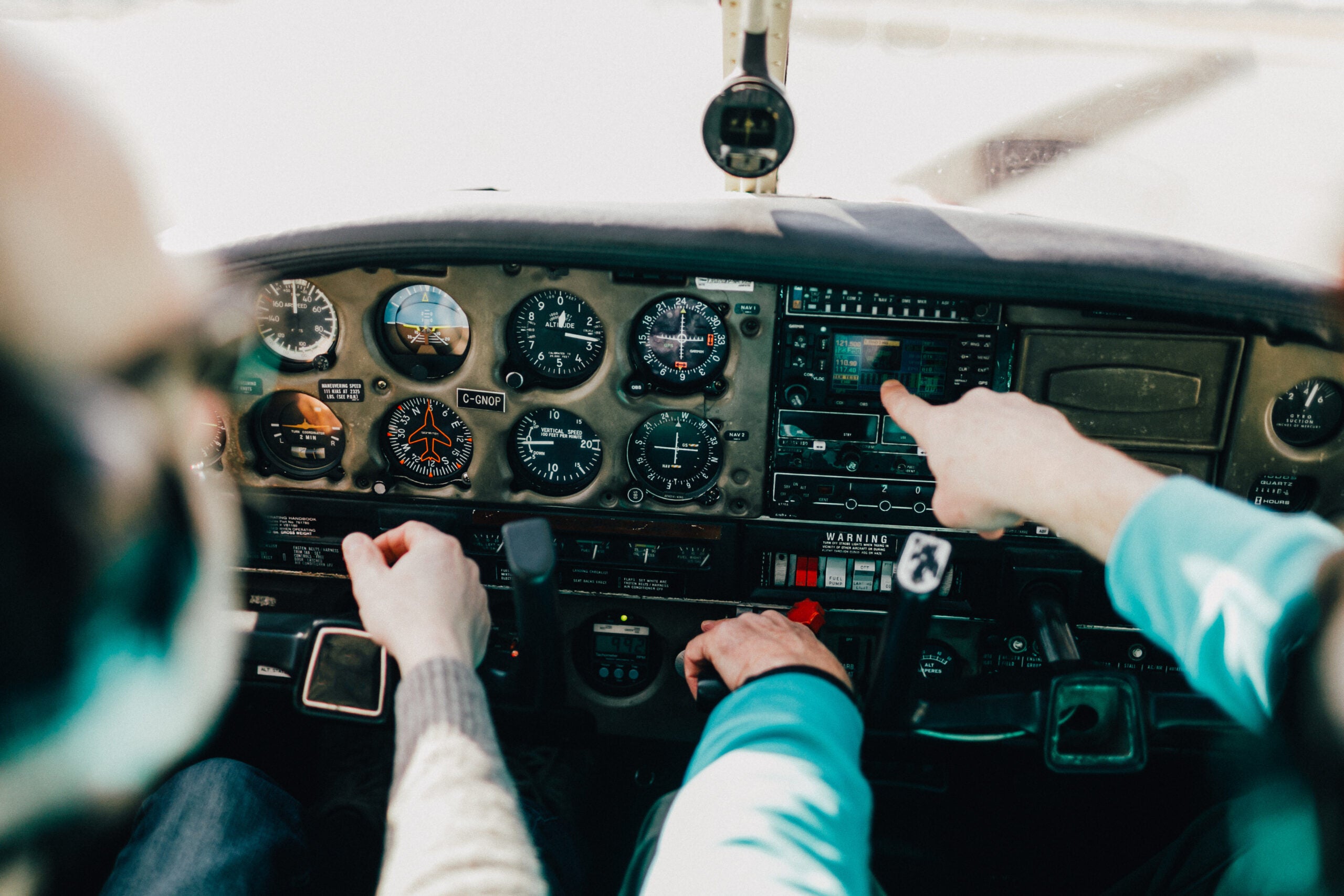 Flight instructor and student operate inside a small Piper aircraft. [Adobe Stock]